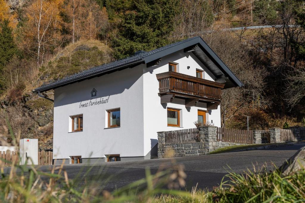 une maison blanche avec un balcon au bord d'une route dans l'établissement Irmas Ferienhäusl, à Längenfeld