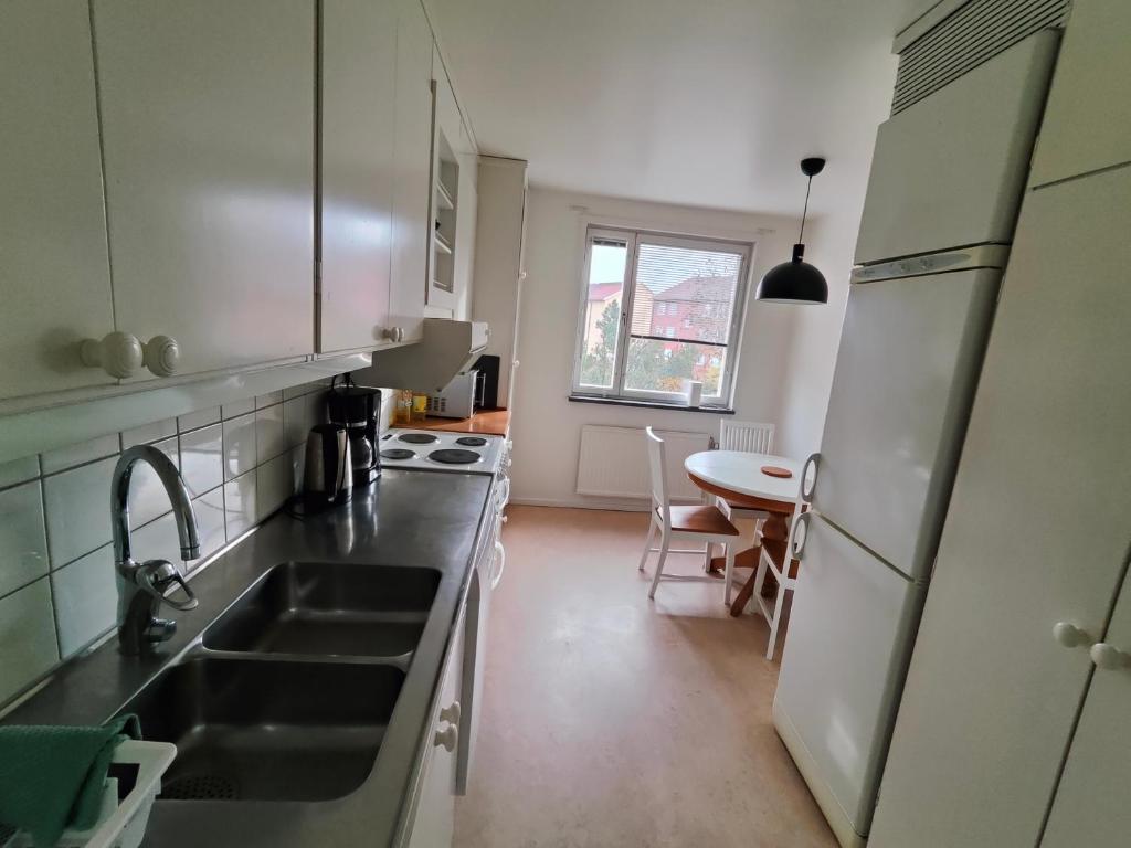 a kitchen with a sink and a table in it at Katrineholm Longstay - Fully equipped 3 room apartment in central Katrineholm in Katrineholm