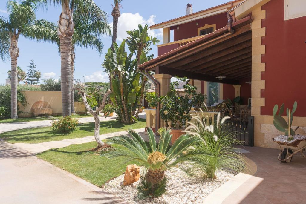 a courtyard with palm trees and a house at L'Ombra dell'Ulivo B&b in Marsala