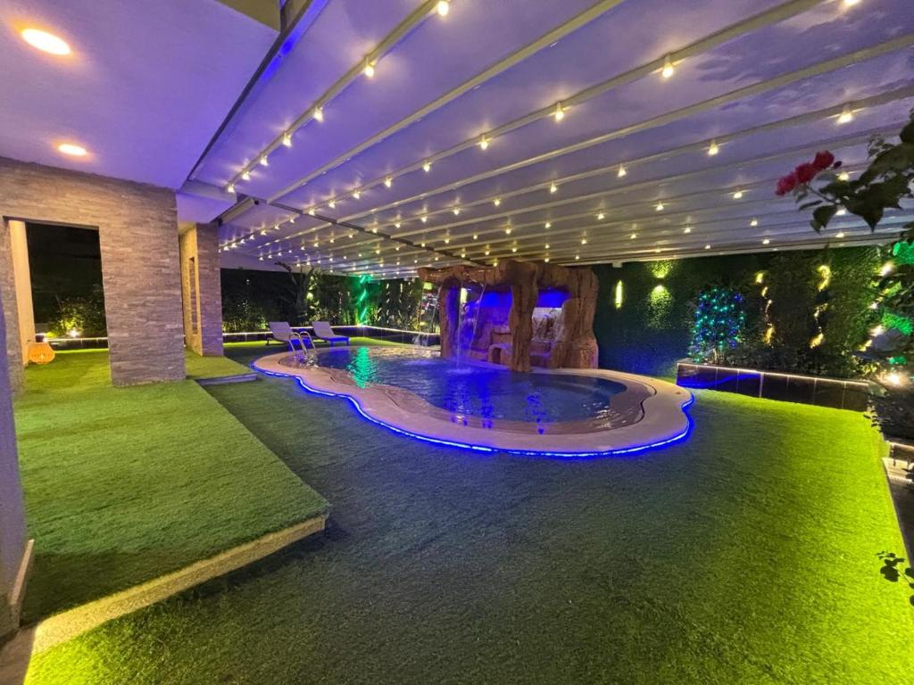ein Haus mit einem Pool in einem Garten mit Lichtern in der Unterkunft 7 BR Smart House with Heated Pool, Waterfall, Garden in Kairo
