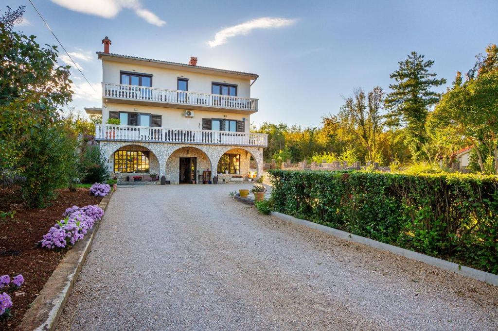 a driveway leading to a large house with a balcony at Apartman Kačić in Sveti Ivan Dobrinjski