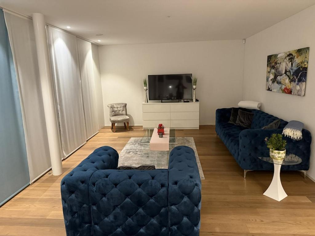 - un salon avec deux canapés bleus et une télévision dans l'établissement Luxuriöse 3,5-Zimmer Wohnung für Familien und Geschäftsreisende mit Glasfaser-Internet, à Cham