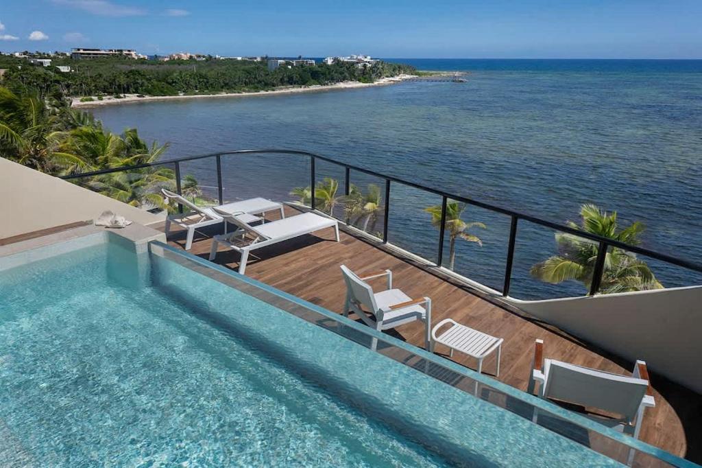 a swimming pool with a view of the ocean at Beachfront 2BR Condo, Private Pool & Tankah Bay in Tulum