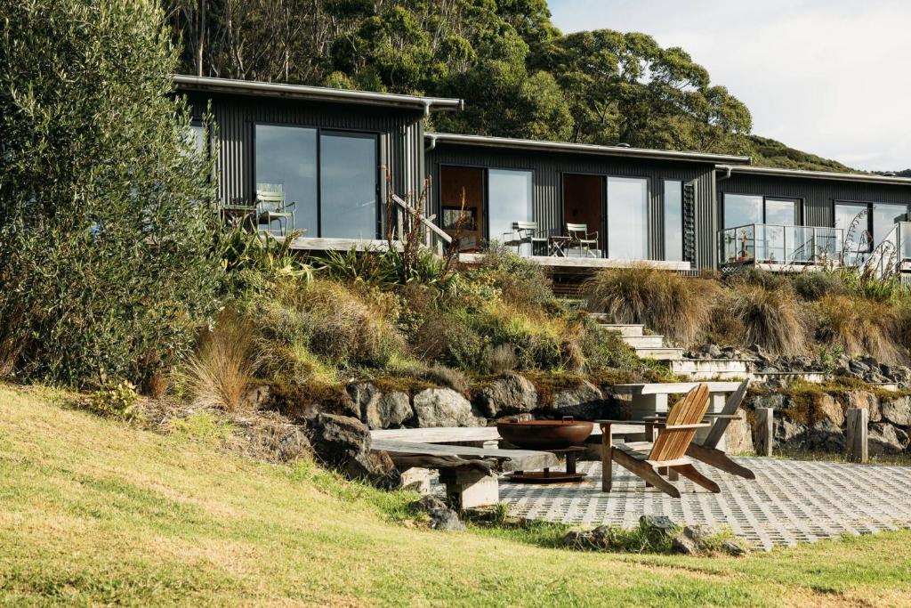 a house on a hill with a picnic table and benches at The Huts in Ahipara