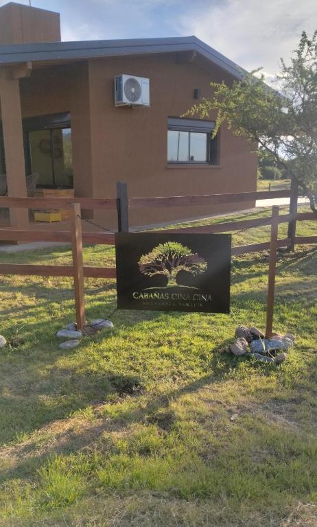 a sign in the grass in front of a house at Cabaña Cina Cina in Villa Larca