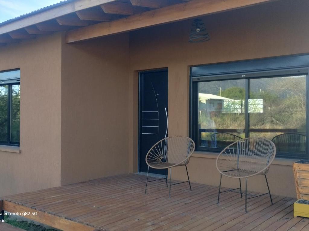 zwei Stühle auf einer Terrasse neben einem Fenster in der Unterkunft Cabaña Cina Cina in Villa Larca