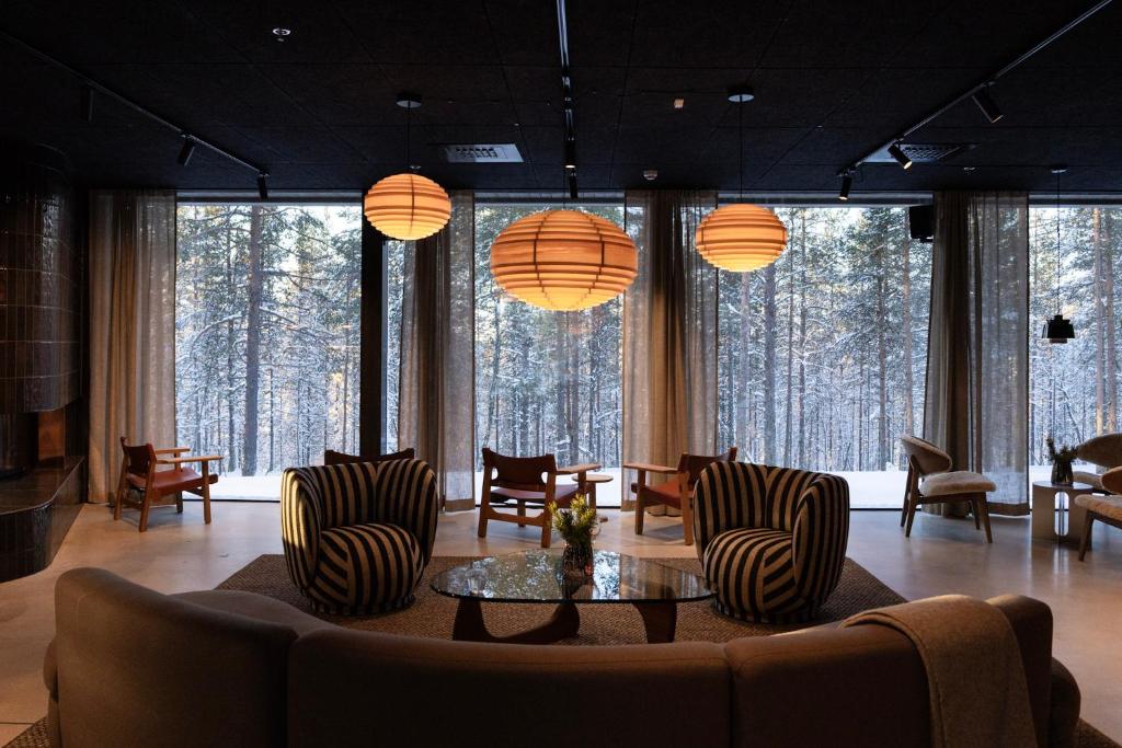 a living room with a couch and chairs and large windows at Gáldu Hotel & Spa in Saariselka