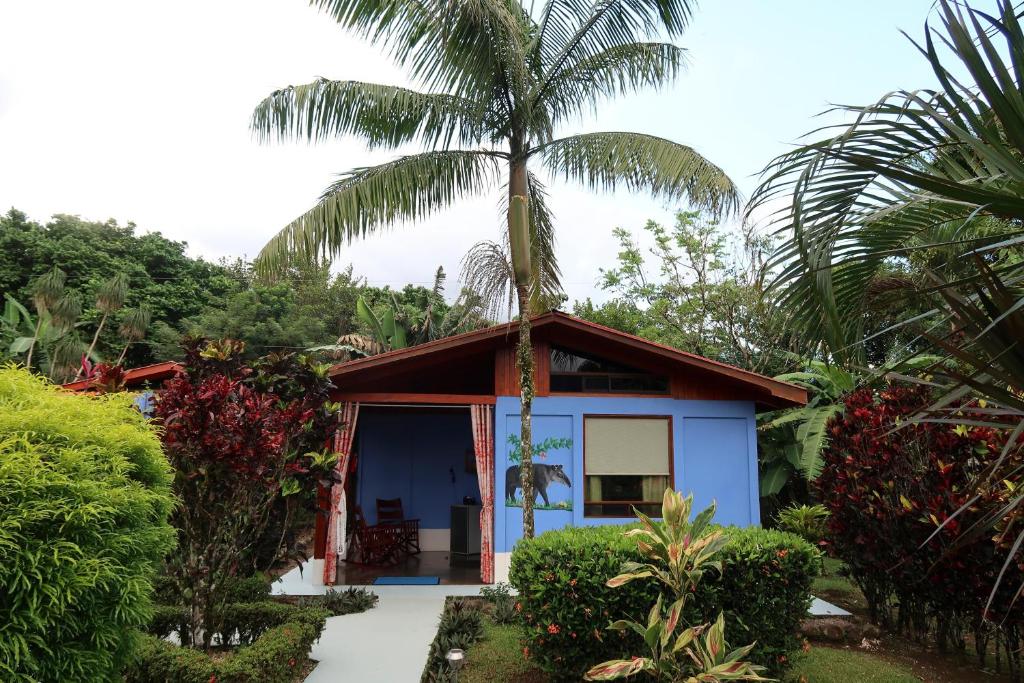a small blue house with a palm tree at Sueño Río Celeste Boutique B&B in Bijagua