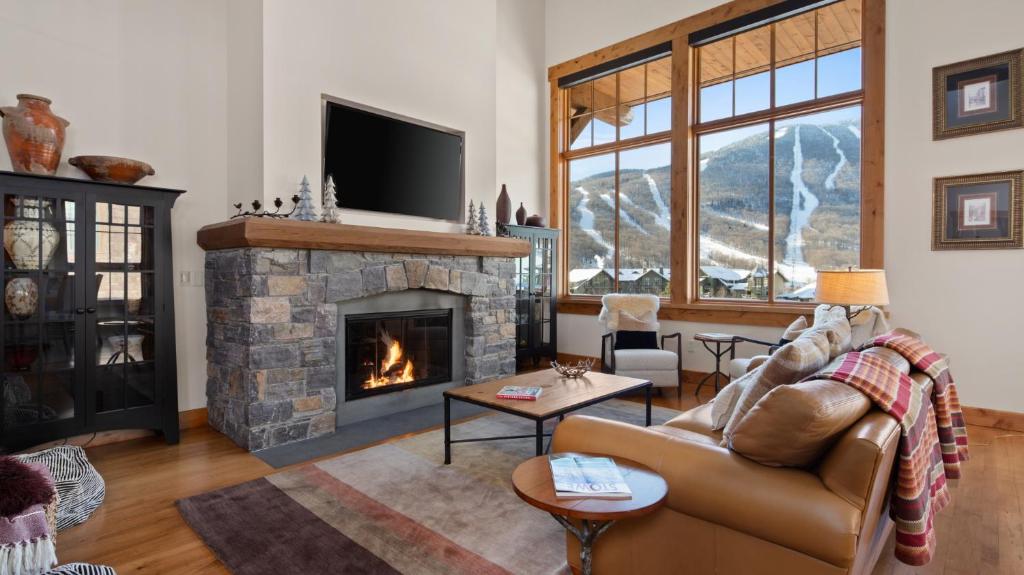 a living room with a couch and a fireplace at STOWE GLOBE 4 BEDROOM LUXURY CABIN SKI IN SKI OUT By Stowe Mountain Rentals in Stowe