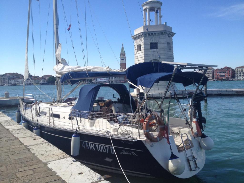 una barca è ormeggiata presso un molo con un faro di Biennale boat & breakfast a Venezia