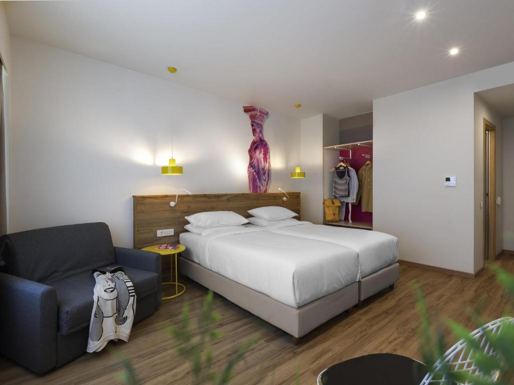 a bedroom with a large bed and a chair at ibis Styles Athens Routes in Athens