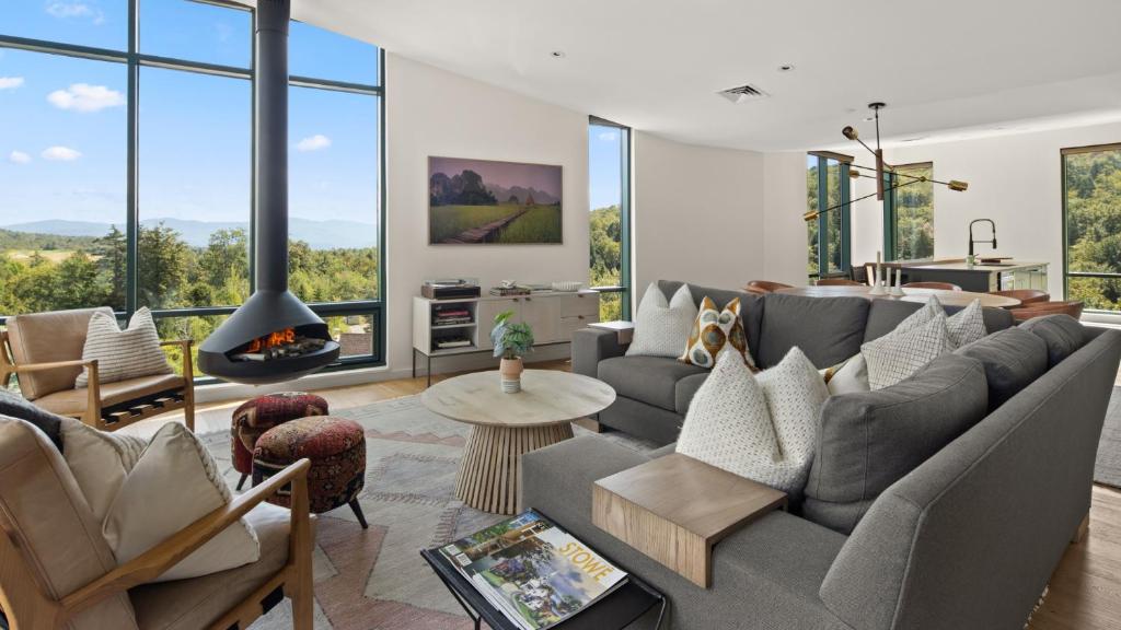 un salon avec un canapé et une cheminée dans l'établissement 411 Spruce Peak Stowe Mountain Resort New Treehouse unit Ski in Ski out 4 bed sleeps 12, à Stowe Mountain