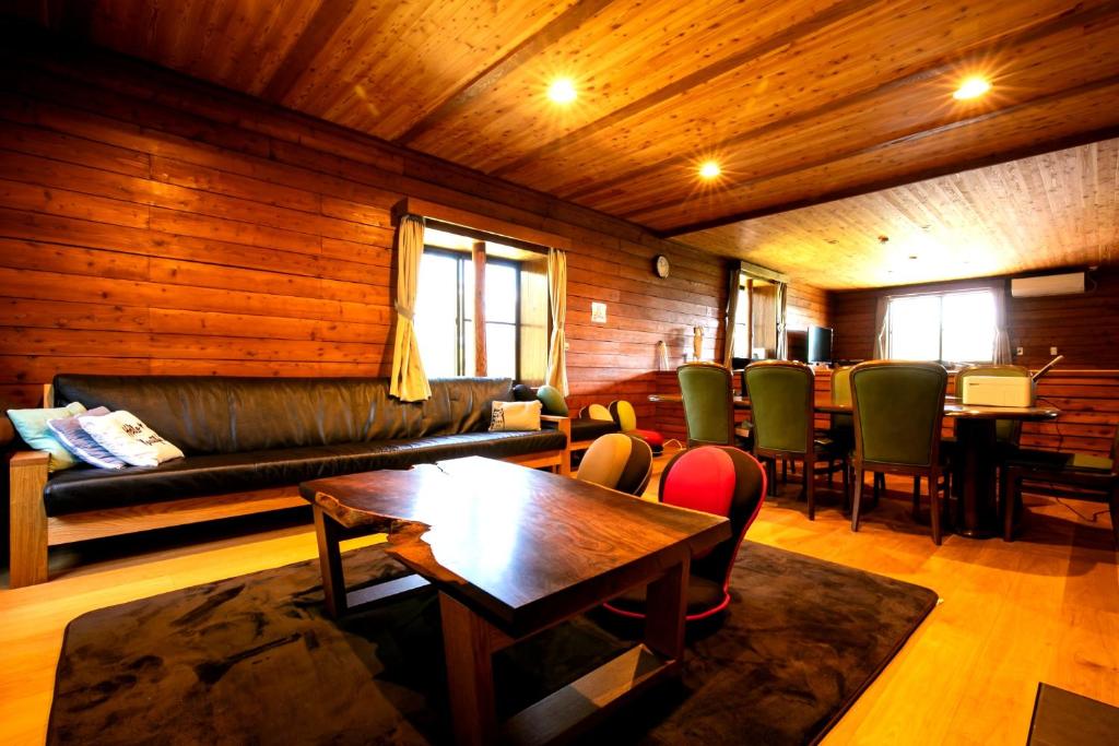 a living room with a couch and a table and chairs at みみずく山荘 Mimizuku Lodge in Myoko