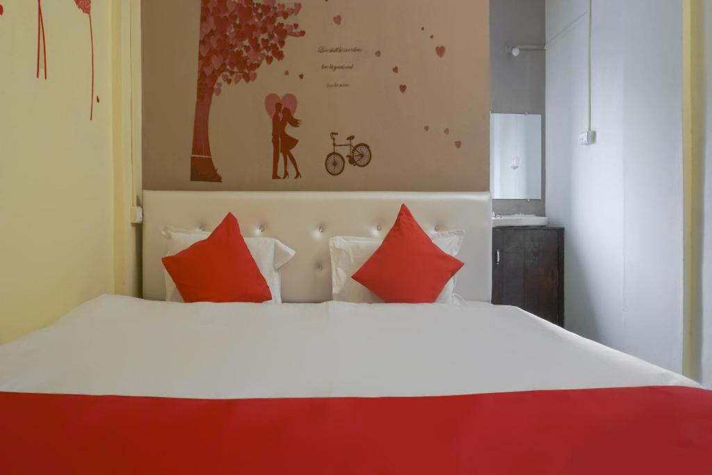 a bedroom with a large white bed with red pillows at Hotel O R K Hotel in Chinchiwad