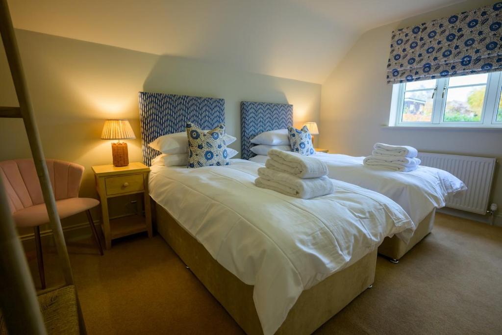 une chambre avec deux lits avec des serviettes dessus dans l'établissement Cragie Cottage- Beautiful Cotswold stone retreat, à Kemerton