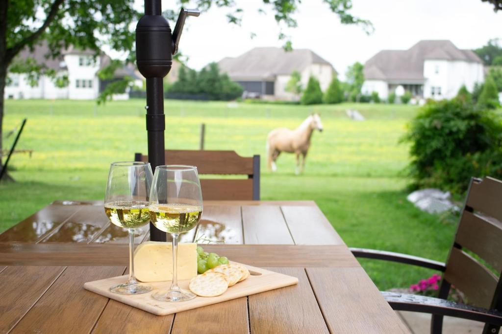 a table with two glasses of white wine and cheese at Hidden Gem Farm Homestead Sleeps 12 &Fresh Produce in Spring Hill