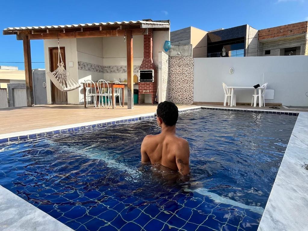 ein junger Mann sitzt in einem Schwimmbad in der Unterkunft Casa Trindade - Residencial Caminho da Praia in Porto Seguro