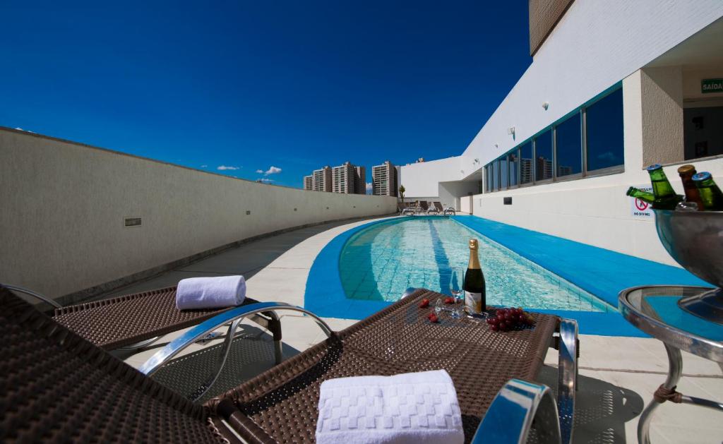 a swimming pool with a table and a bottle of wine at Go Inn Taguatinga in Taguatinga