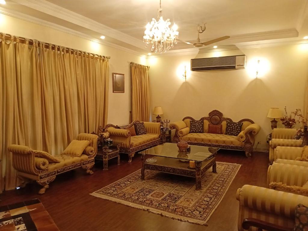 un soggiorno con divani e un lampadario di Naim Ullah Tiwana a Lahore