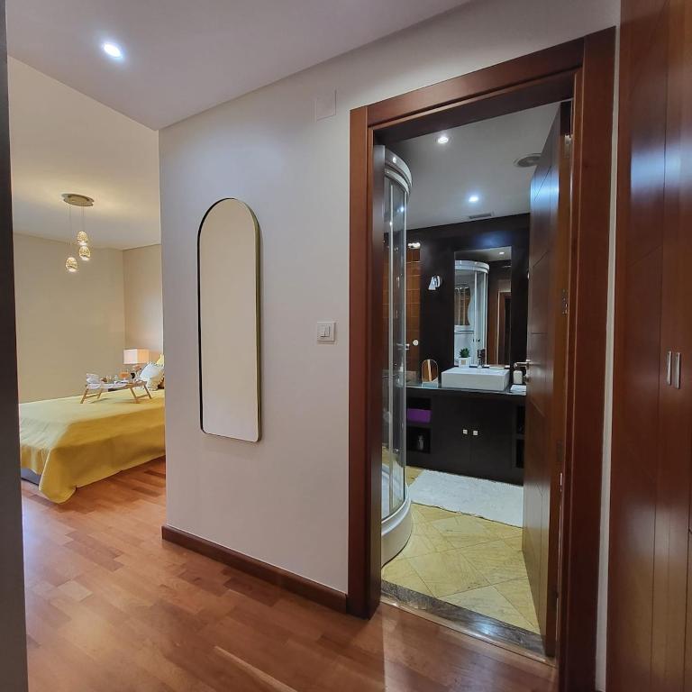 Zimmer mit einem Bad mit einem Spiegel und einem Schlafzimmer. in der Unterkunft Spacious 2BR near Odivelas Metro with Balcony in Odivelas