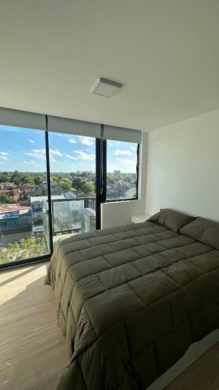a bedroom with a large bed and large windows at Bright on the avenue in Mar del Plata