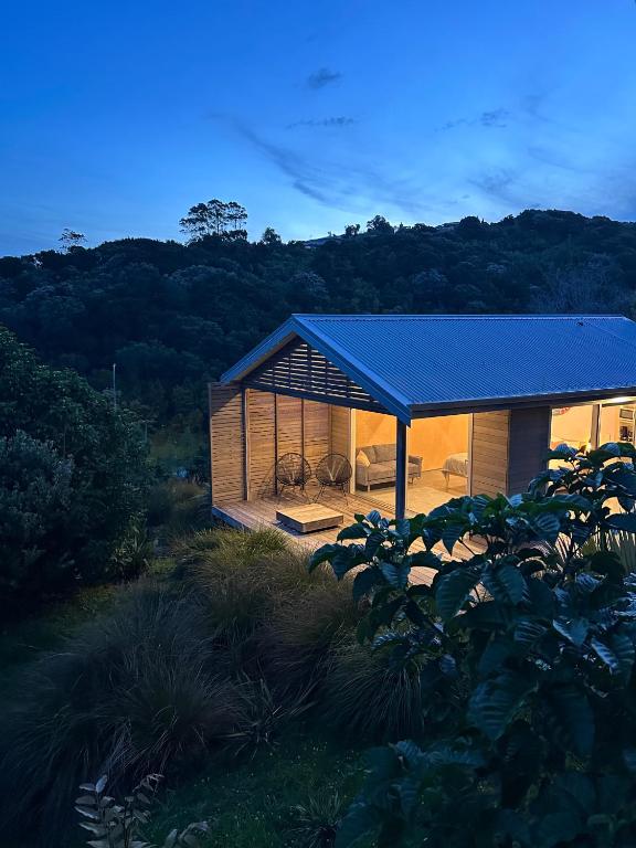 a small house with a blue roof in a field at One O One Cabins, Waiheke Island in Oneroa