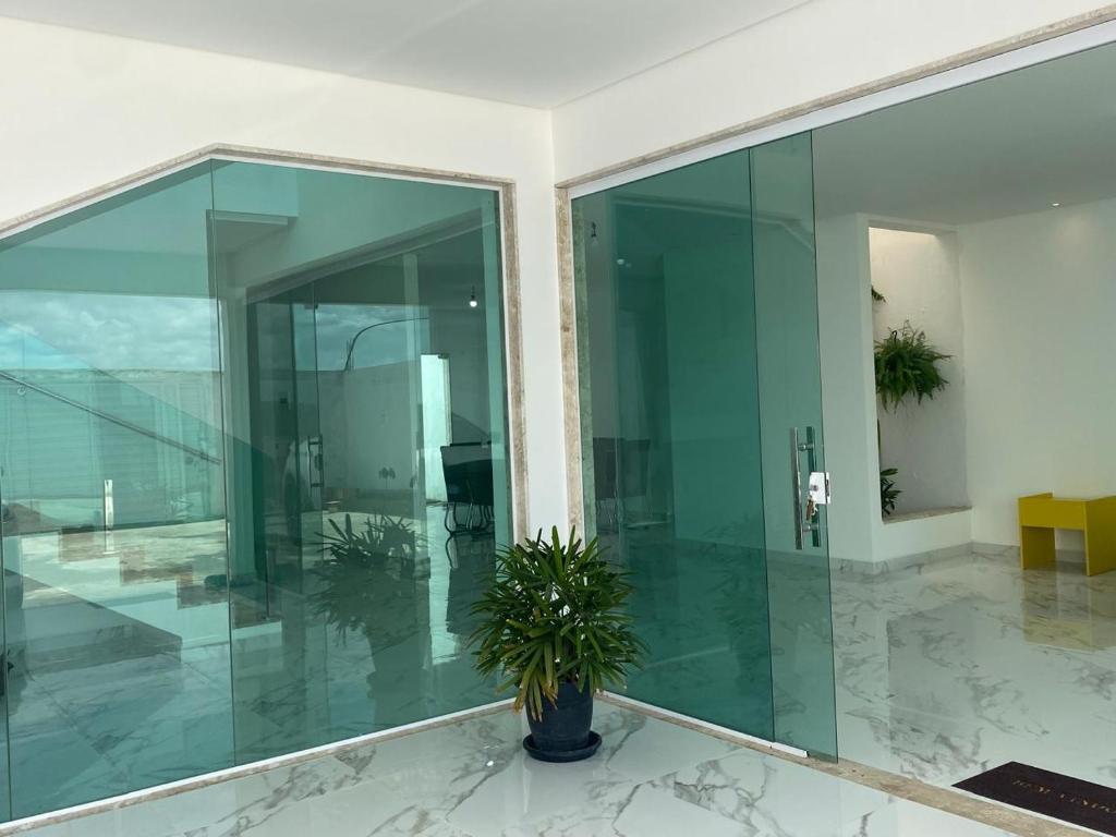 eine große Glaswand in einem Gebäude mit einer Topfpflanze in der Unterkunft Casa ampla e luxuosa em Caldas do Jorro in Tucano