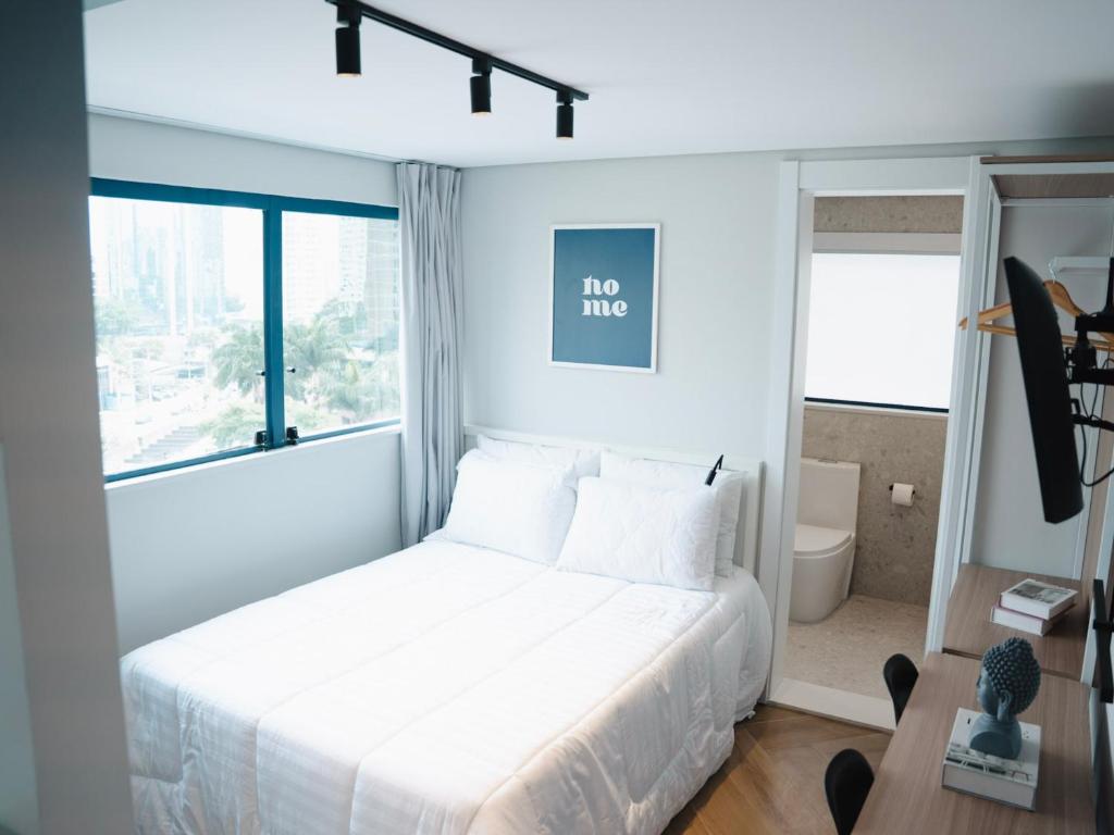 um quarto com uma cama branca e uma janela em Apê Itaim Bibi - Soft Opening em São Paulo