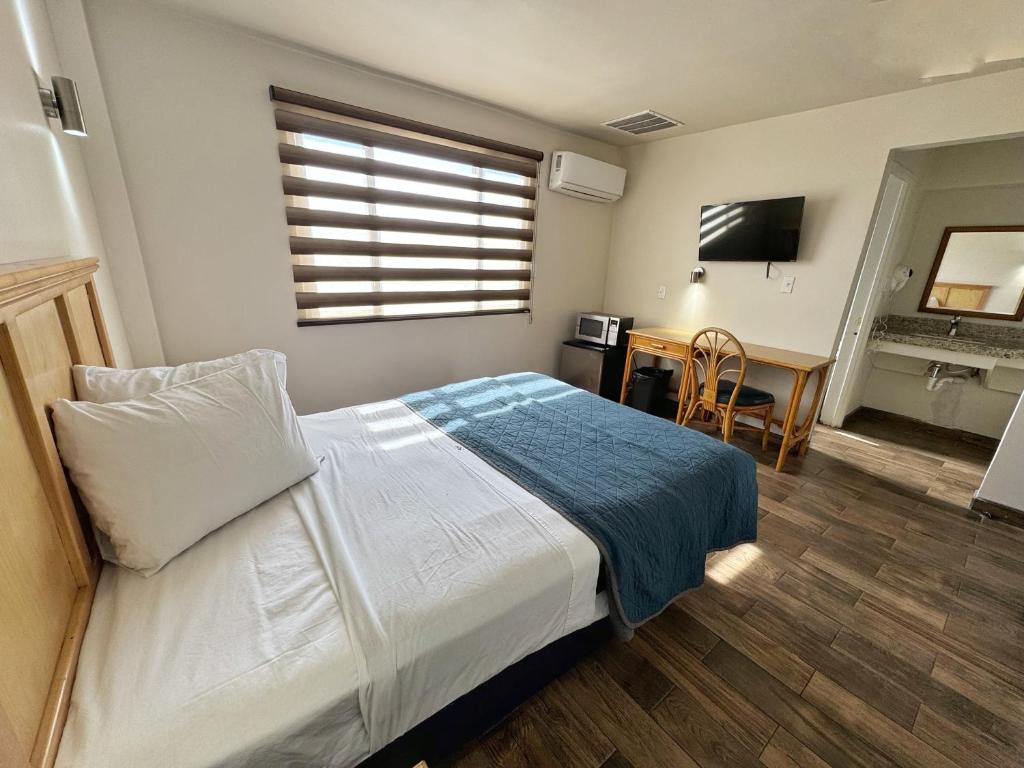 a bedroom with a bed and a desk and a television at Hotel Paris in Tijuana