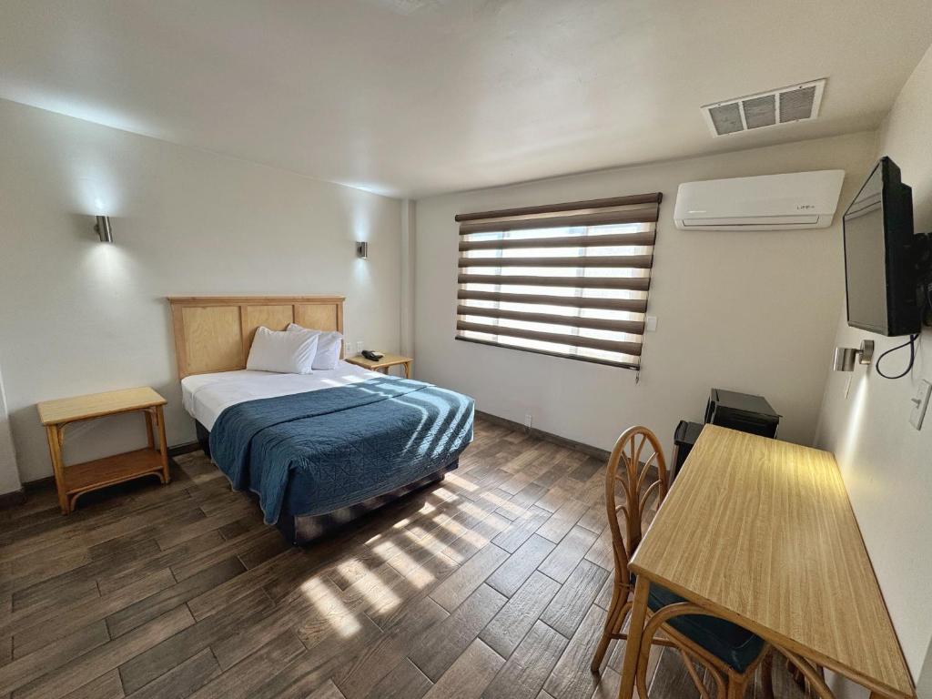 a bedroom with a bed and a table and a window at Hotel Paris in Tijuana
