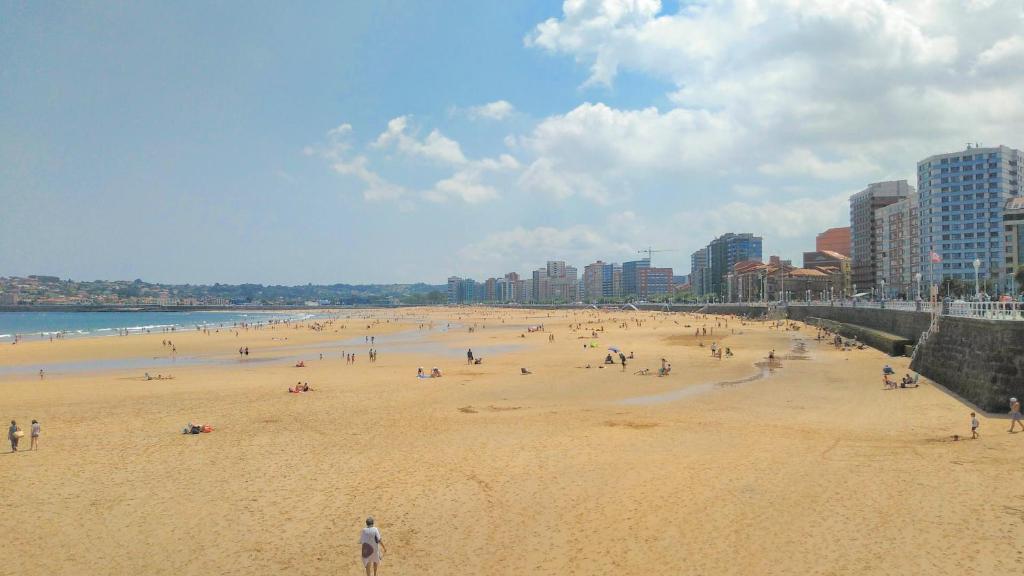 un grande gruppo di persone su una spiaggia di En el centro entre el puerto y las playas a Gijón