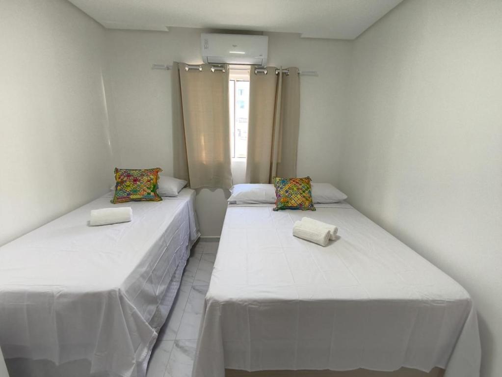 two twin beds in a room with a window at Hotel Pousada Velas ao Mar in Maceió