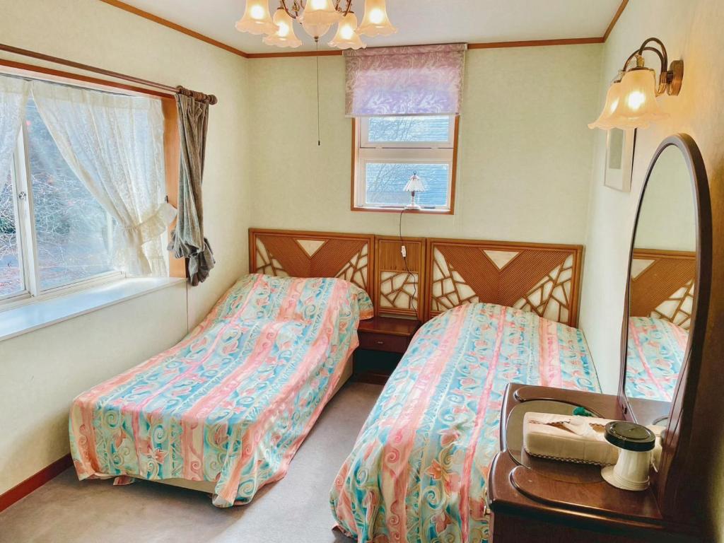 a bedroom with two beds and a mirror at Guesthouse PAW in Nagano