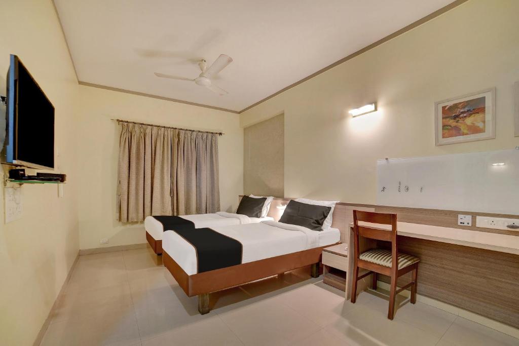 a bedroom with a bed and a desk and a television at Townhouse Oak Pune Railway Station Formerly Kapil Residency in Pune