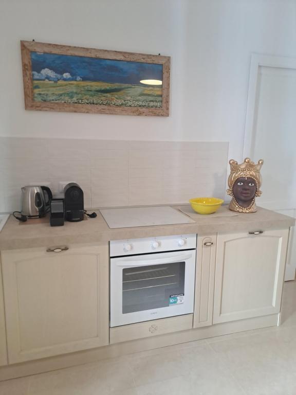 eine Küche mit weißen Schränken und einer Theke mit einer Mikrowelle in der Unterkunft ORTIGIA LUXURIs DOMUs in Syrakus