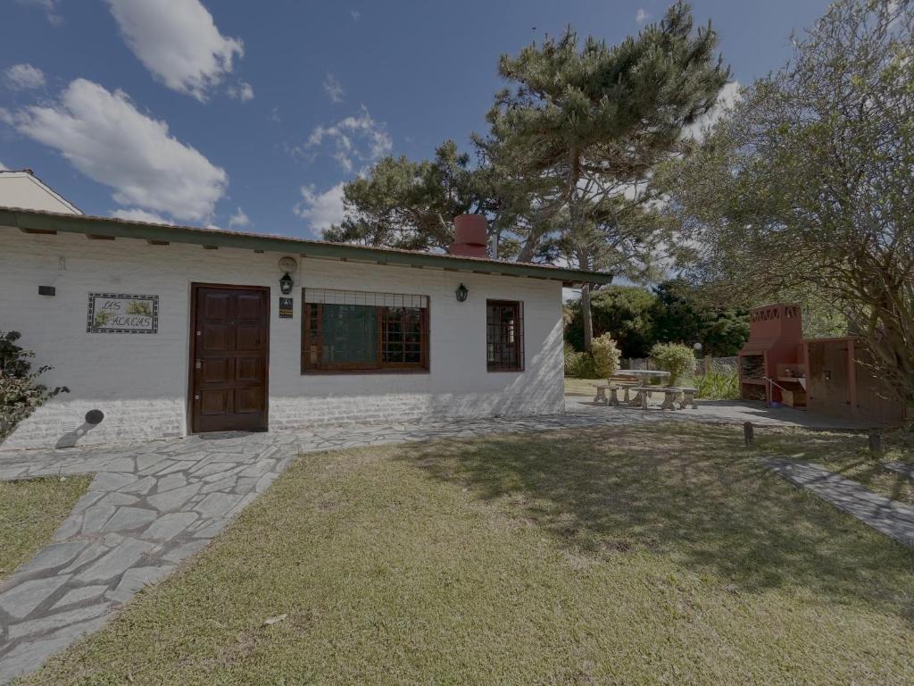 ein kleines weißes Haus mit einer Terrasse und einem Hof in der Unterkunft La casita en la playa in Villa Gesell