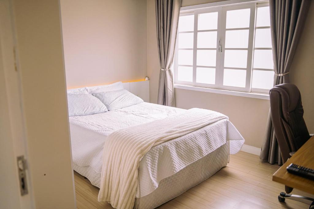 een slaapkamer met een wit bed en een raam bij Apartamento 1 Quarto Canasvieiras in Florianópolis