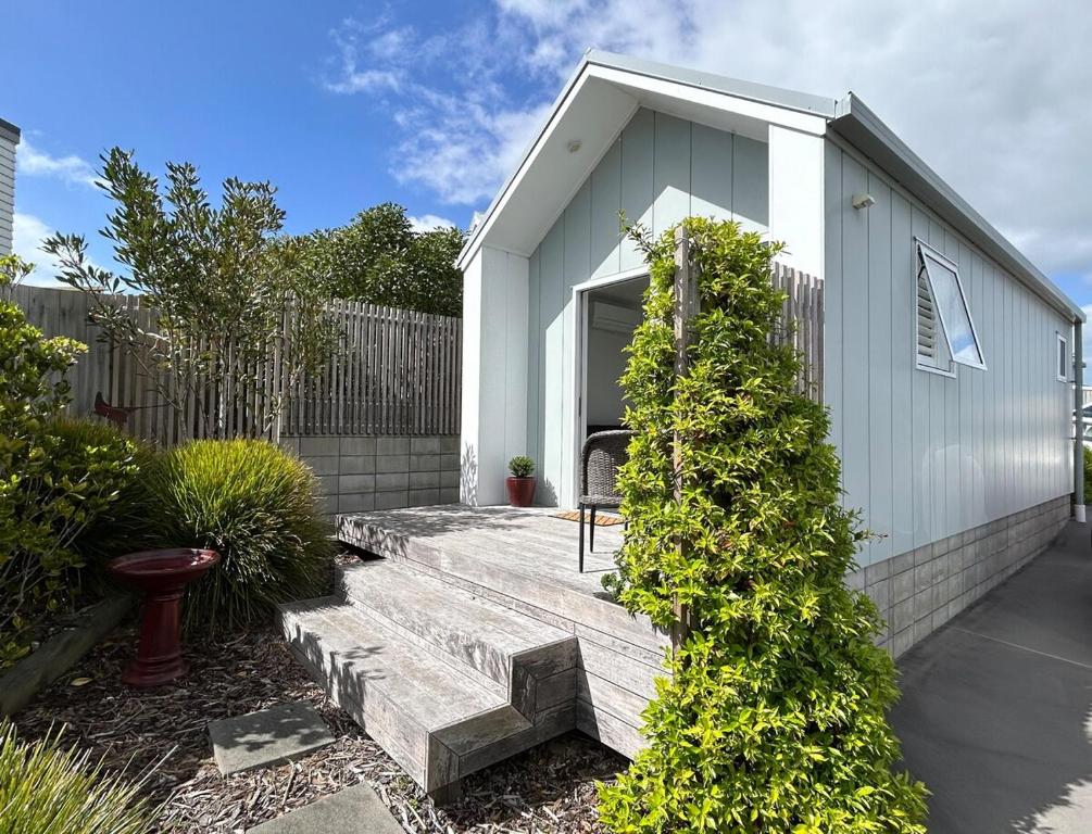 a small white building with a bench in a yard at Modern & Central 'Nautical' Chalet - Mangawhai Heads in Mangawhai