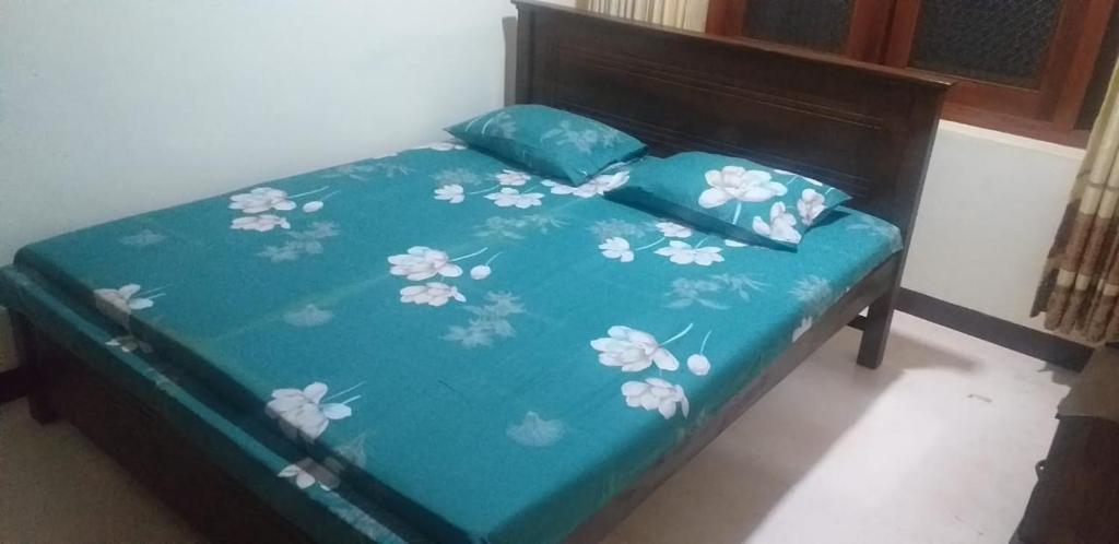 Una cama con un edredón azul con flores. en Indivilla, en Kalutara