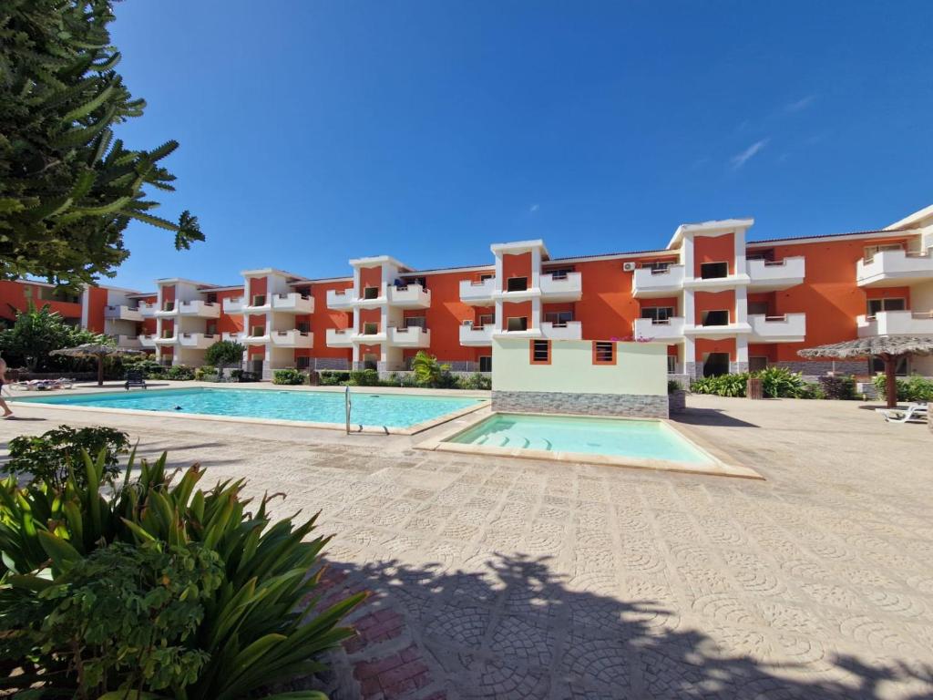 an apartment complex with a swimming pool in front of a building at T2 Djadsal Bloco Laranja Perto da Praia e Centro in Santa Maria