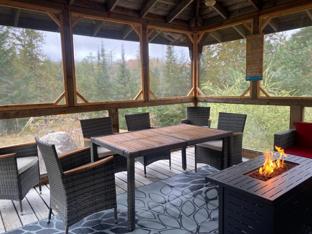 a screened in porch with a wooden table and chairs at Tait Lake Retreat - Luxury Lakeside Home in Turriff