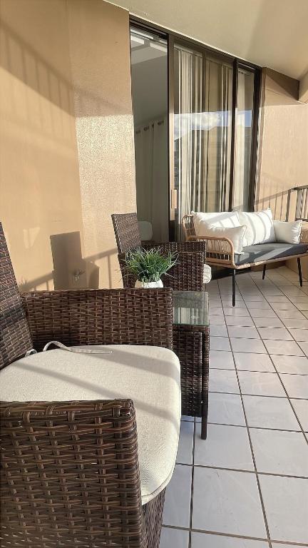 a balcony with wicker chairs and a table on a building at New Ocean View Condominium Free parking in Honolulu