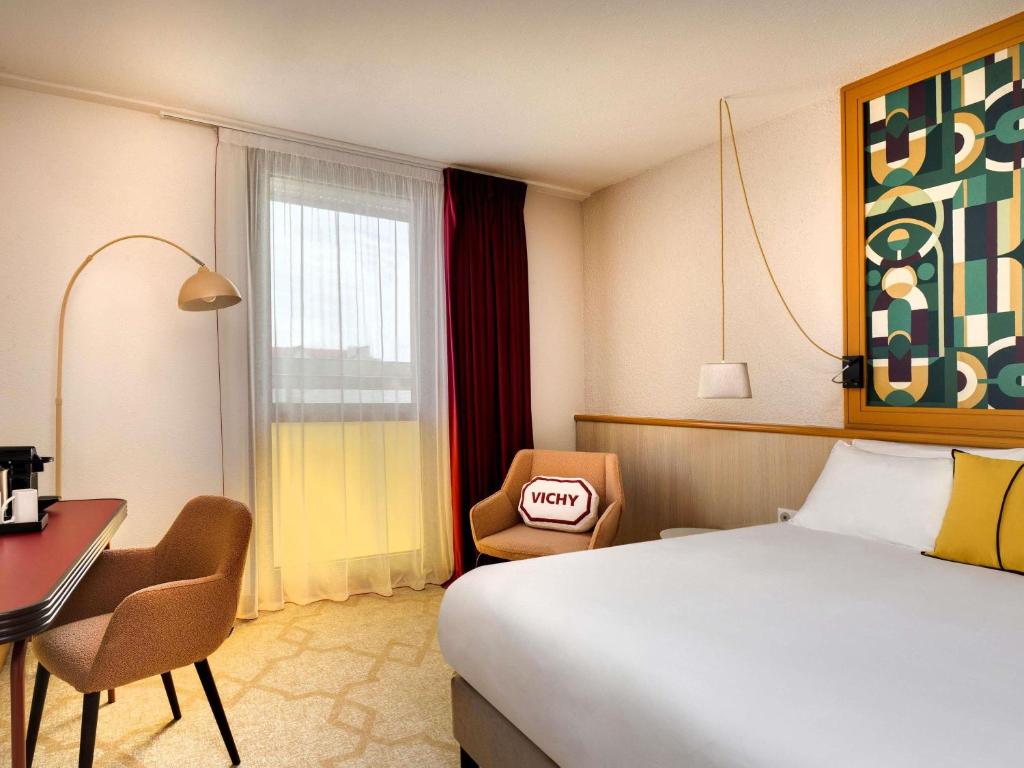 a hotel room with a bed and a desk and chair at Mercure Vichy in Vichy