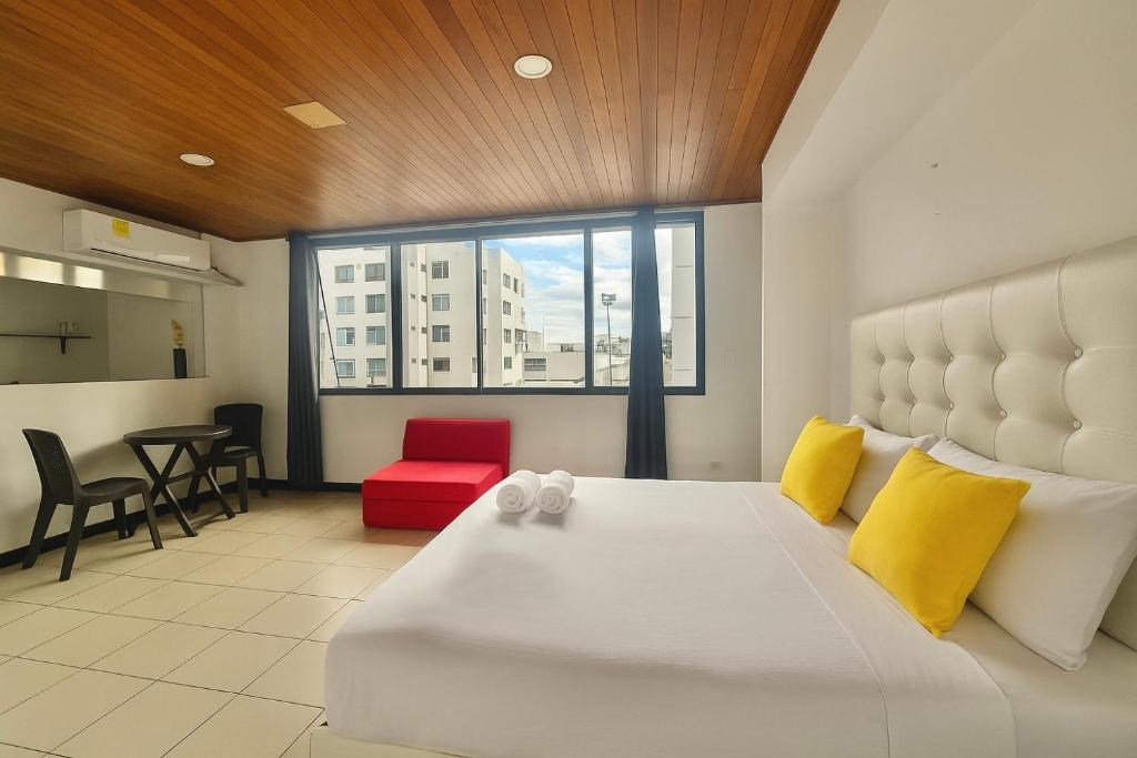 a bedroom with a large white bed with yellow and red pillows at Las casas de tomate Cartagena in Cartagena de Indias