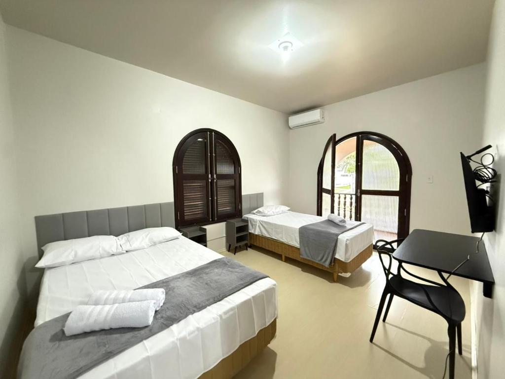 a bedroom with two beds and a desk in it at Pousada Dona Lidia Express in Campo Mourão