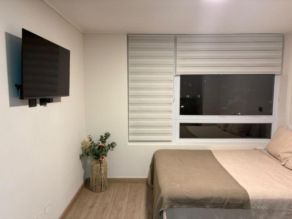 a bedroom with a bed and a window with a flat screen tv at Central space in Concepción