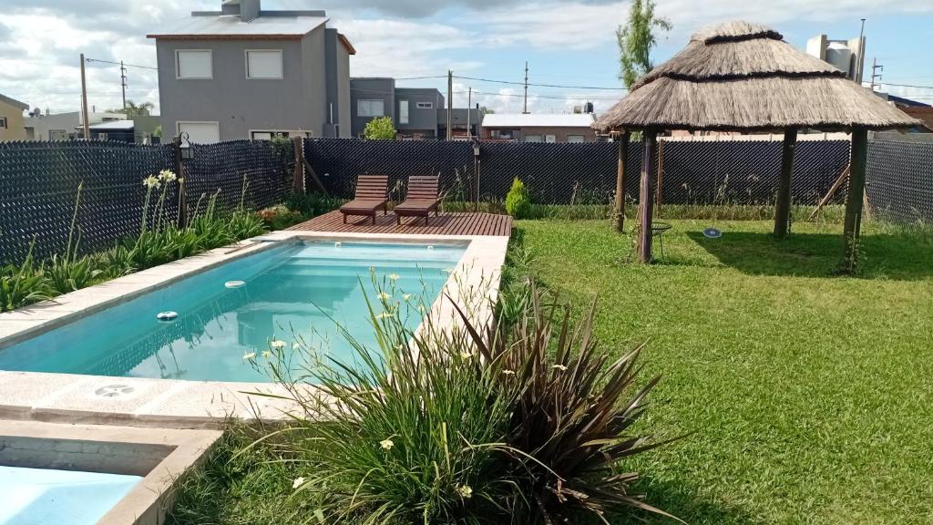 a swimming pool in a yard with two chairs and a gazebo at La casita de las flores in Roldán