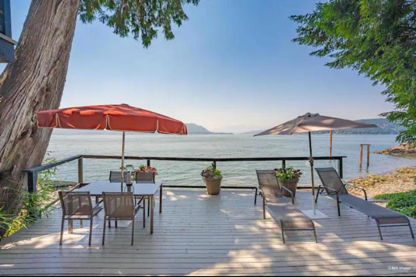une terrasse en bois avec une table, des chaises et un parasol dans l'établissement SALT COTTAGE Waterfront Guest House with Superb Views, à West Vancouver