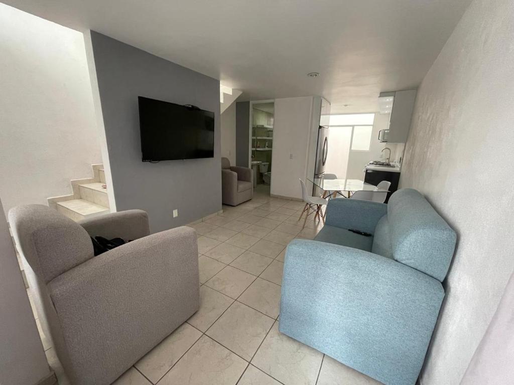 - un salon avec deux chaises et une télévision à écran plat dans l'établissement casa santacruz, à Guadalajara