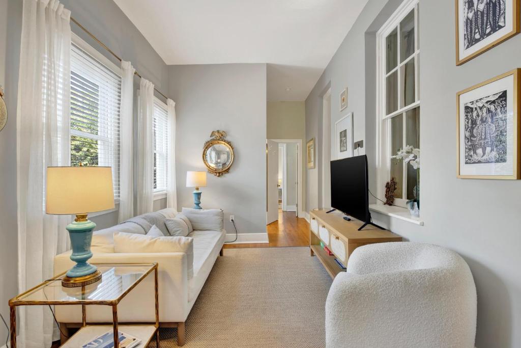 ein Wohnzimmer mit weißen Möbeln und einem Fernseher in der Unterkunft Hideaway on Jones in Savannah